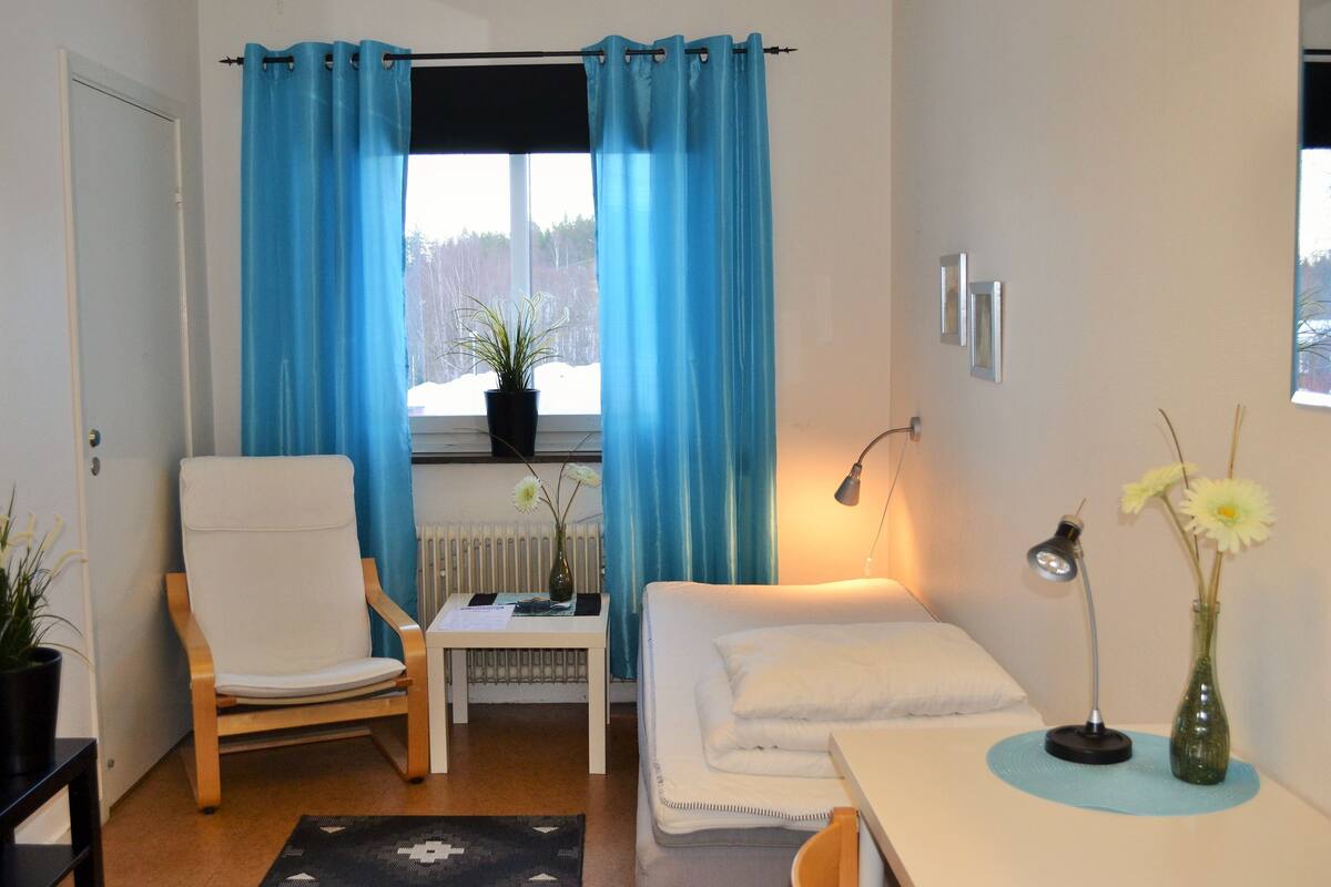 Une pièce comprenant une chaise blanche, une petite table avec une plante, un canapé blanc et un bureau avec une lampe et un vase.