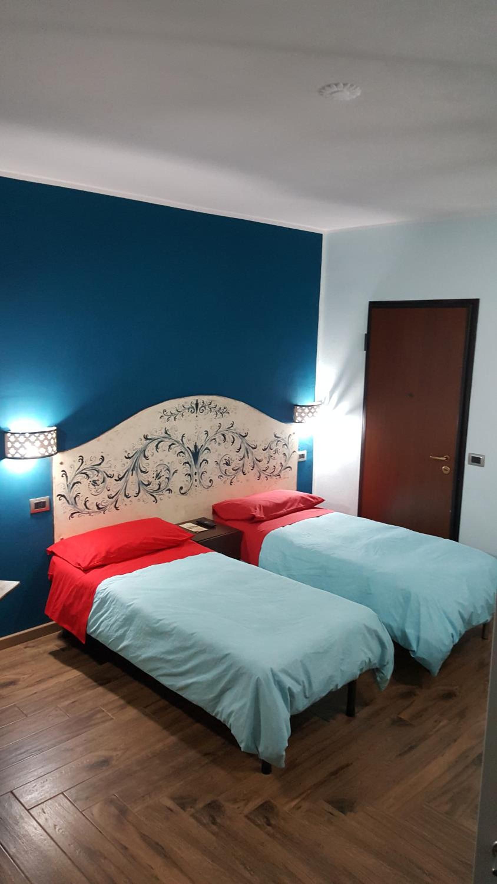 Una habitación con cama, dos mesitas de noche y una puerta.