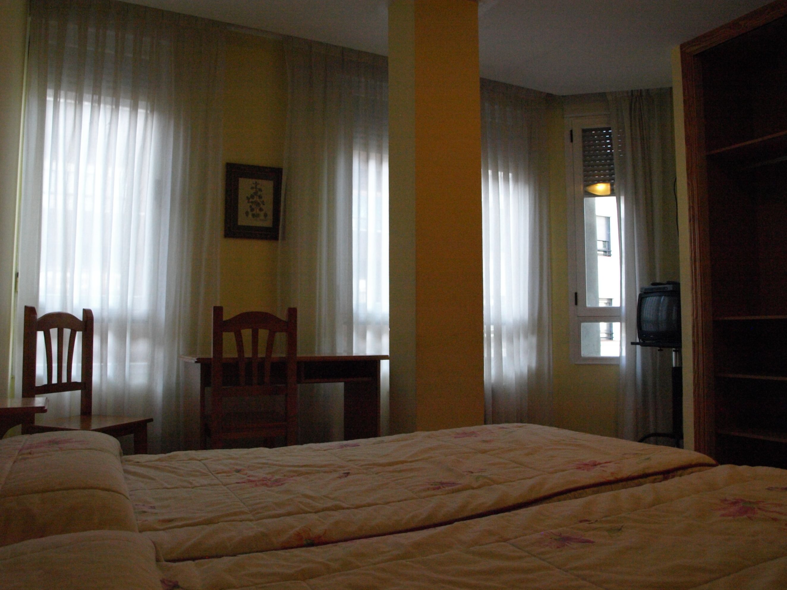 Ein Zimmer mit zwei Betten, einem Schreibtisch, einem Stuhl und einem Fernseher.