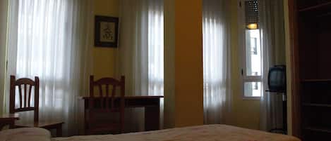 Una habitación con dos camas, un escritorio, una silla y un televisor.