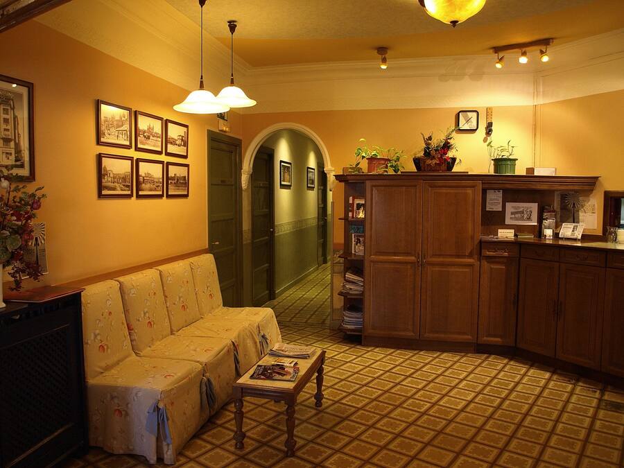 A cozy hotel lobby with a sofa, a wooden cabinet, and framed pictures on the wall.