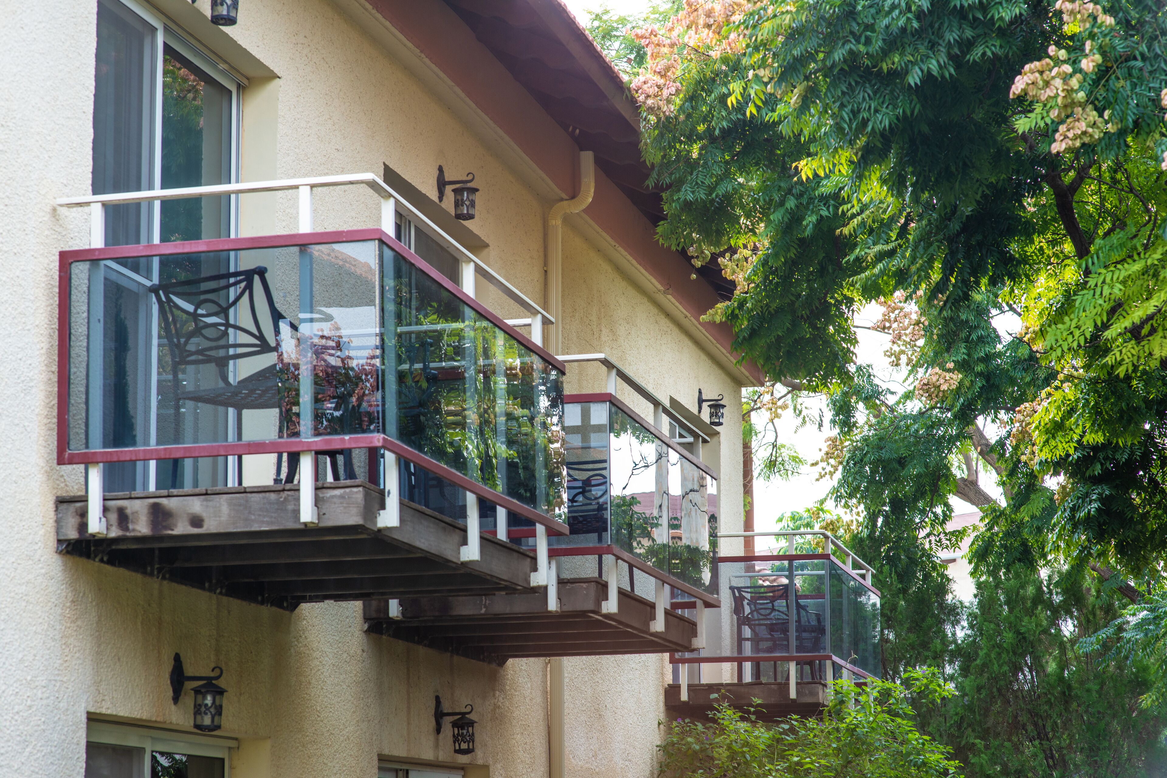 Un edificio con varios balcones, cada uno con barandillas de vidrio y estructura metálica.
