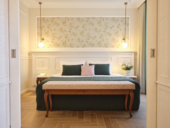 Een keurig opgemaakt slaapkamer met een groot bed, een nachtkastje, een bankje en een wandlamp.
