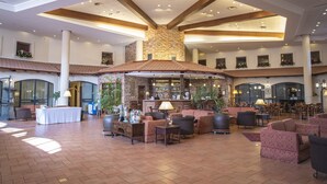 Een ruime lobby met een centrale bar, comfortabele zithoeken en een hoog plafond met zichtbare balken.