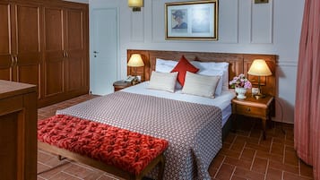 Habitació d'hotel amb un llit gran, dues taules de nit amb làmpades, un armari de fusta i un quadre encimbellat a la paret.