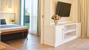 Een hotelkamer met een bed, een aan een kast bevestigde televisie en een raam met gordijnen.