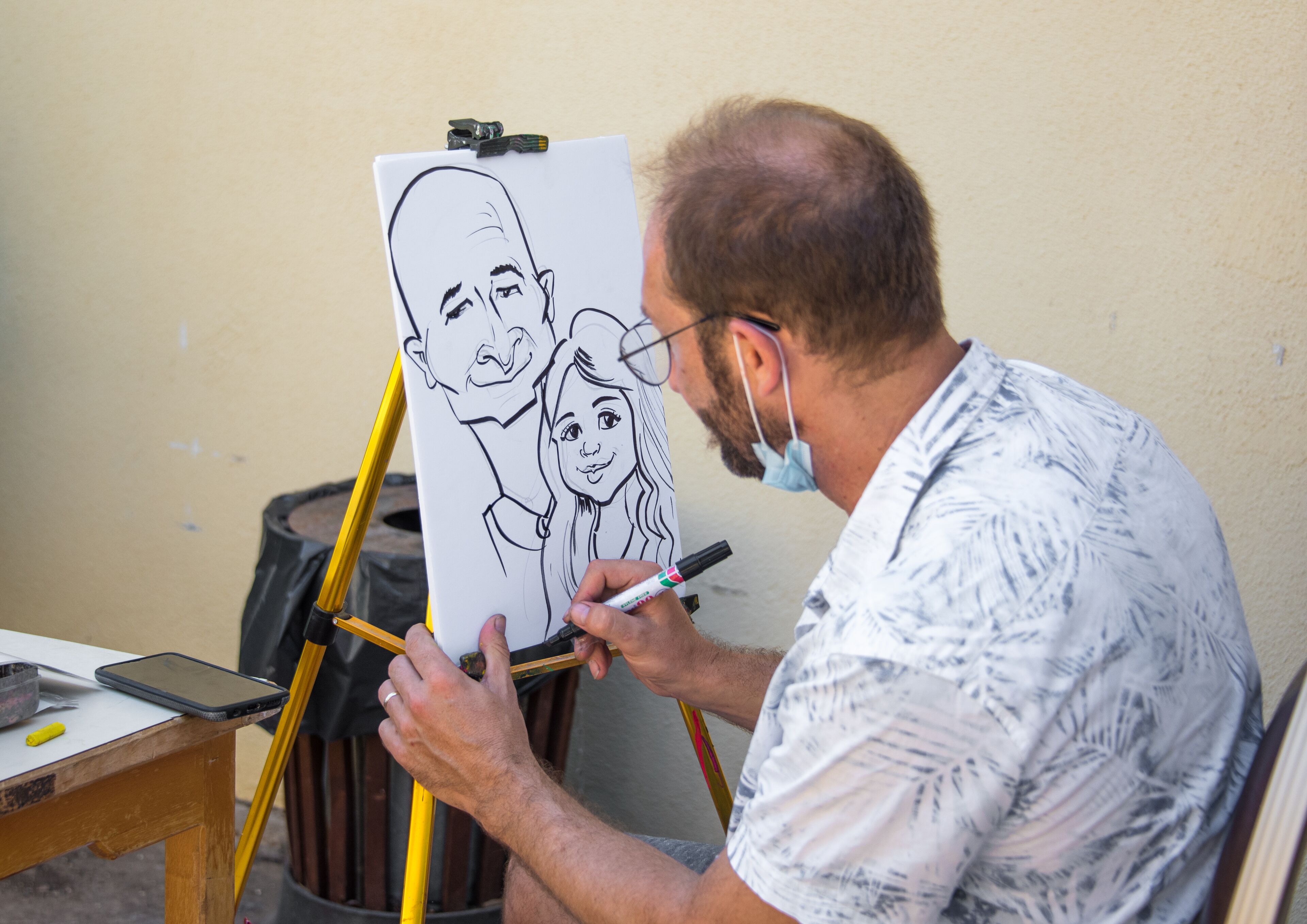 A person drawing on a whiteboard with a black marker.
