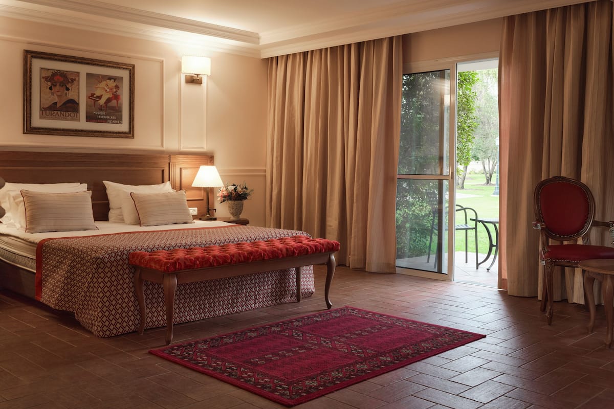 Une chambre d’hôtel avec un lit, une table de chevet, une lampe, une chaise et une vue sur l’extérieur.