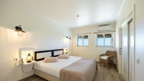 A bedroom with a bed, bedside lamps, a chair, and a window.