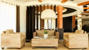 A modern lounge area with wicker furniture, a central coffee table, and a large hanging light fixture.