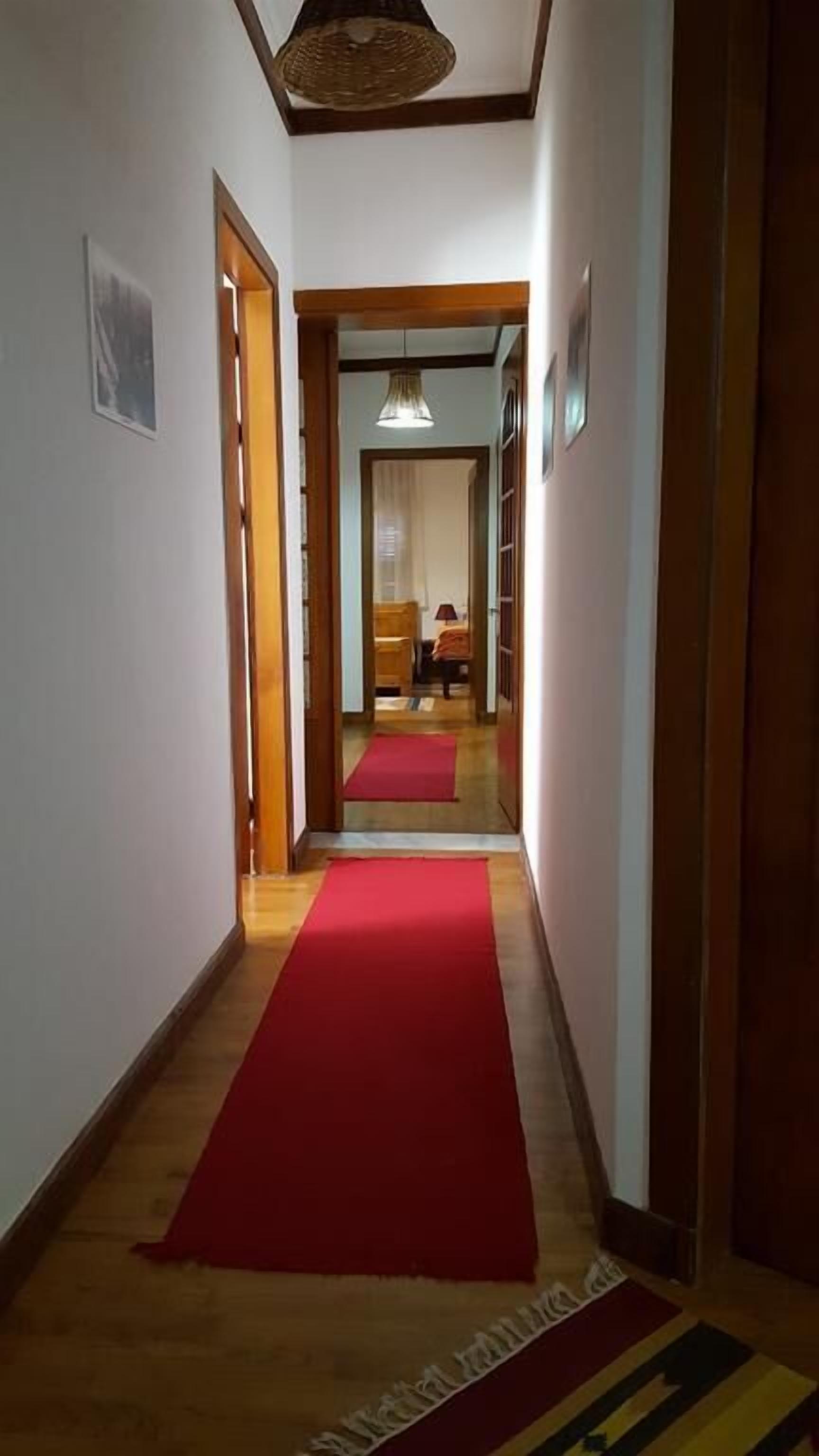 A hallway with a red carpet leading to a bedroom.