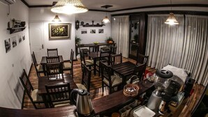 Un comedor con mesas y sillas de madera, una cafetera y lámparas colgantes.