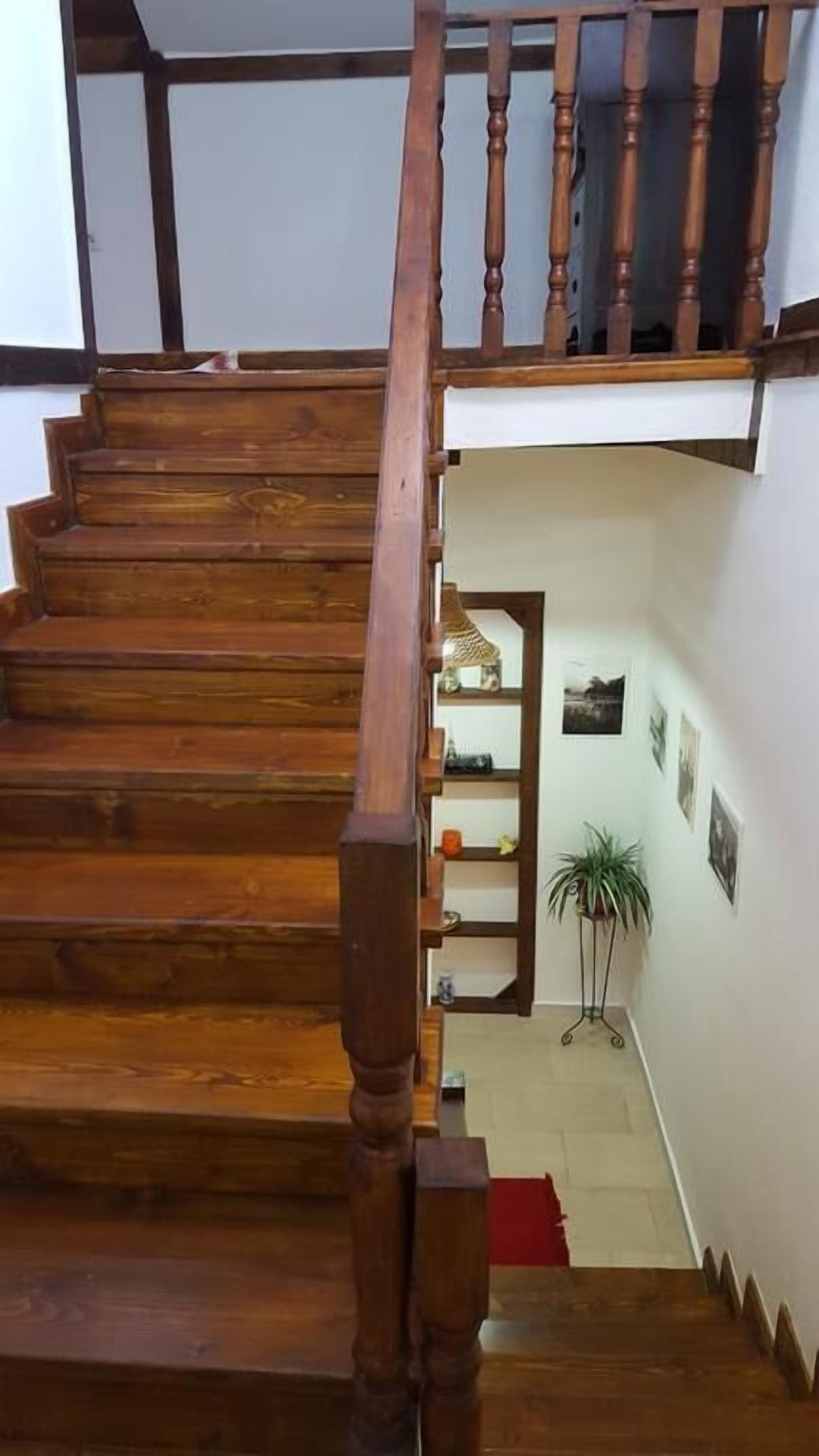 Un escalier en bois, doté d’une rampe, mène à un palier.