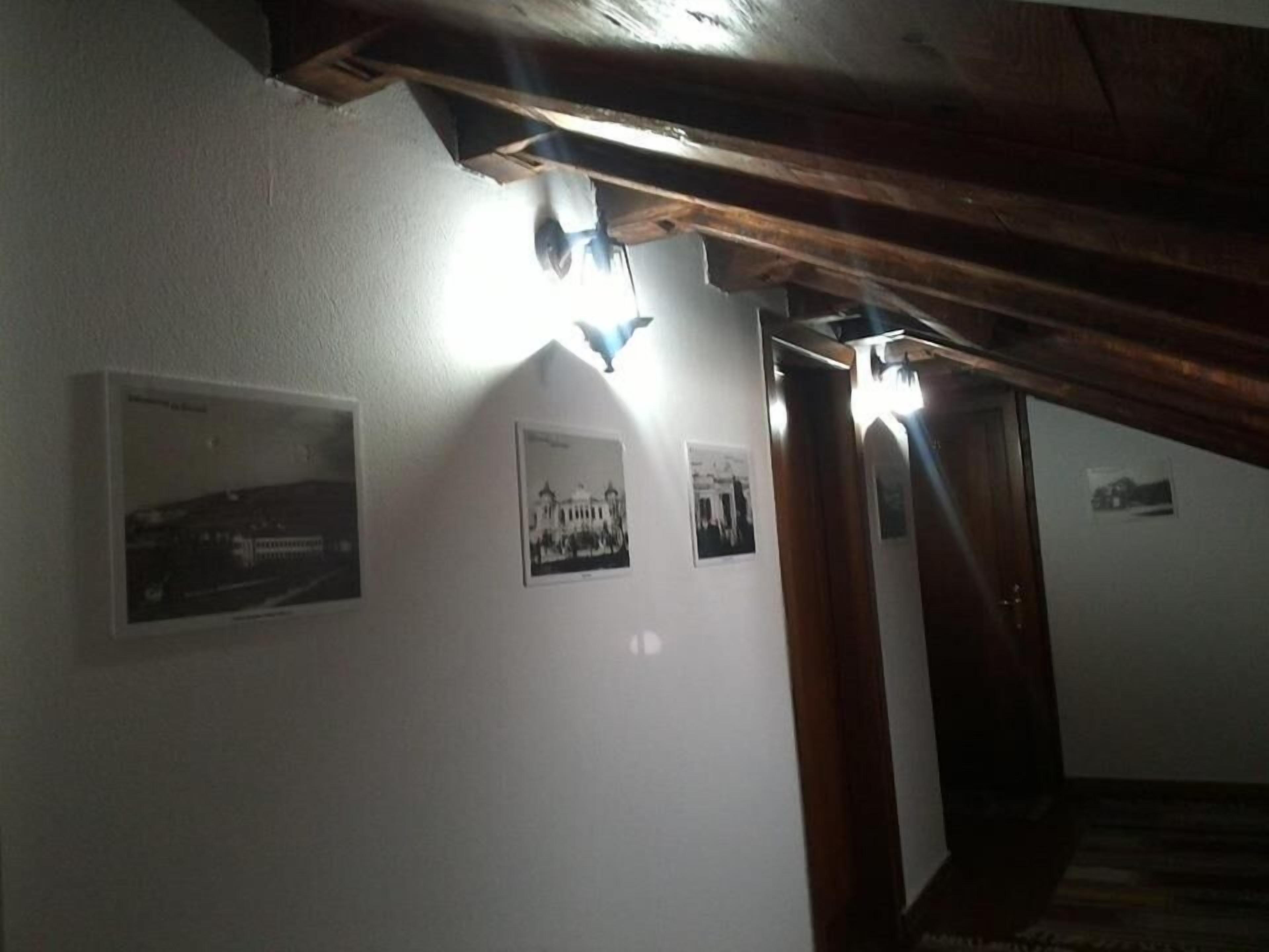 Un pasillo con vigas de madera, paredes blancas y tres fotografías blanco y negro.