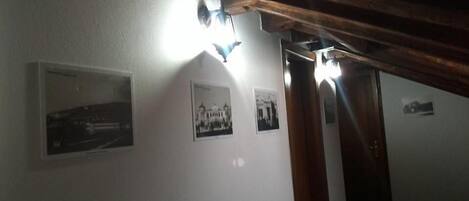 Un pasillo con vigas de madera, paredes blancas y tres fotografías blanco y negro.