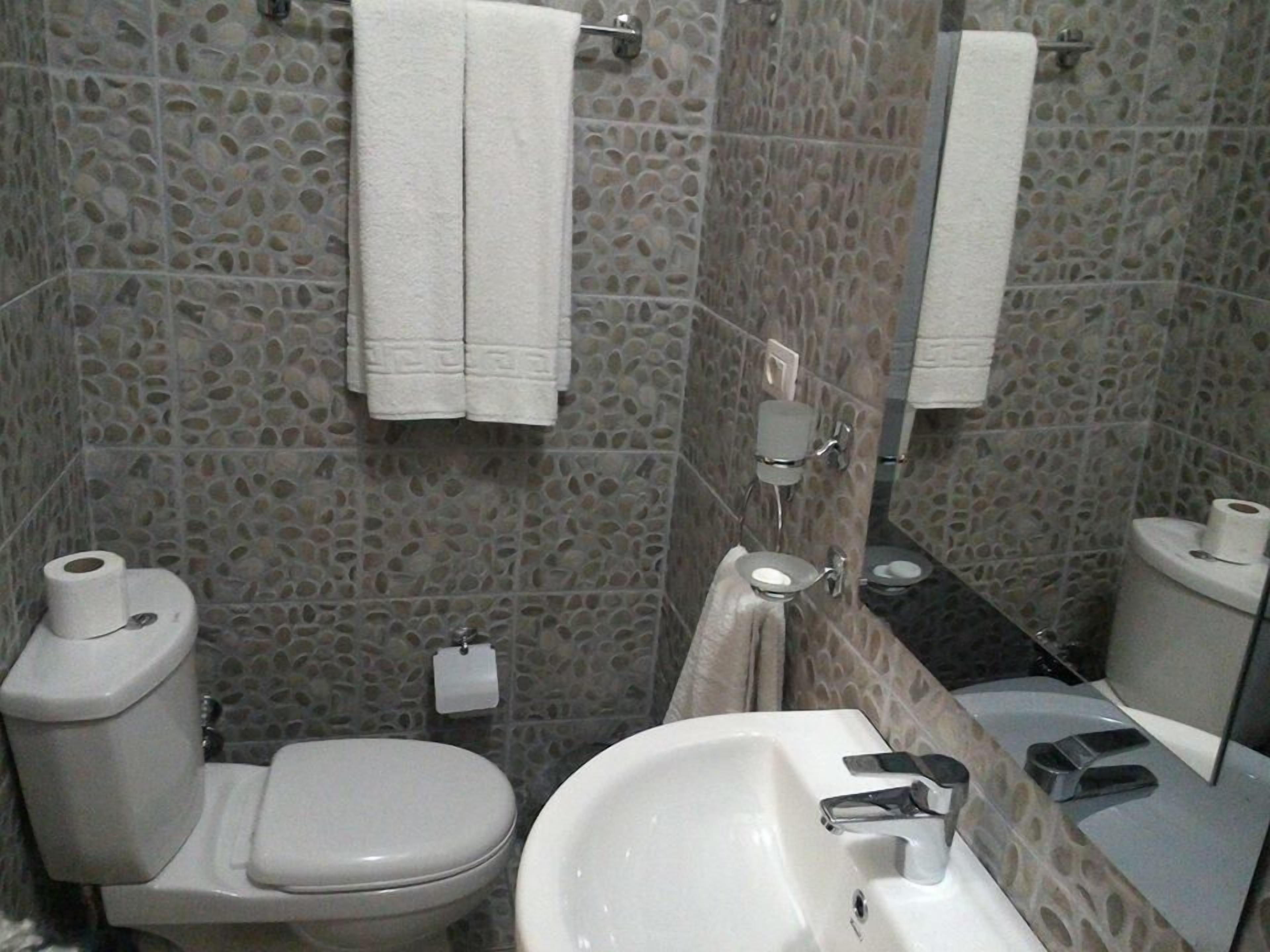 Un baño con inodoro, lavamanos y espejo.