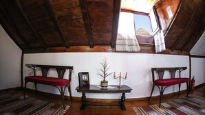 Acogedor dormitorio en el ático con vigas de madera, una pequeña mesa con candelabro y dos sillas.