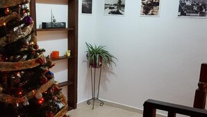 Una sala de estar con un árbol de Navidad decorado, una alfombra roja, una escalera y una pared con fotografías enmarcadas.