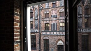 Vista de un edificio de ladrillo con ventanas de arco y diseños decorativos.