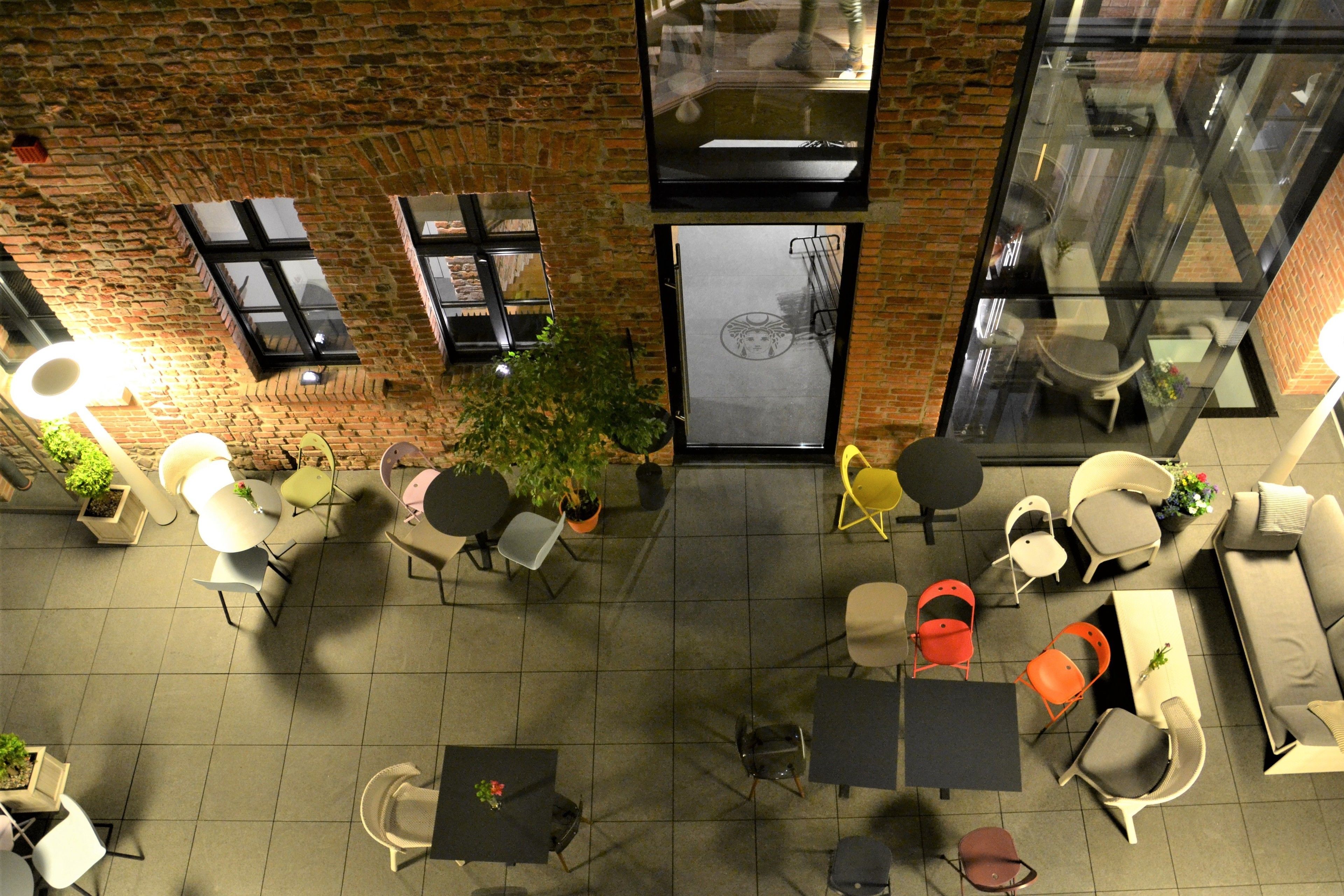 An outdoor seating area with tables and chairs, a brick wall, and a glass door.