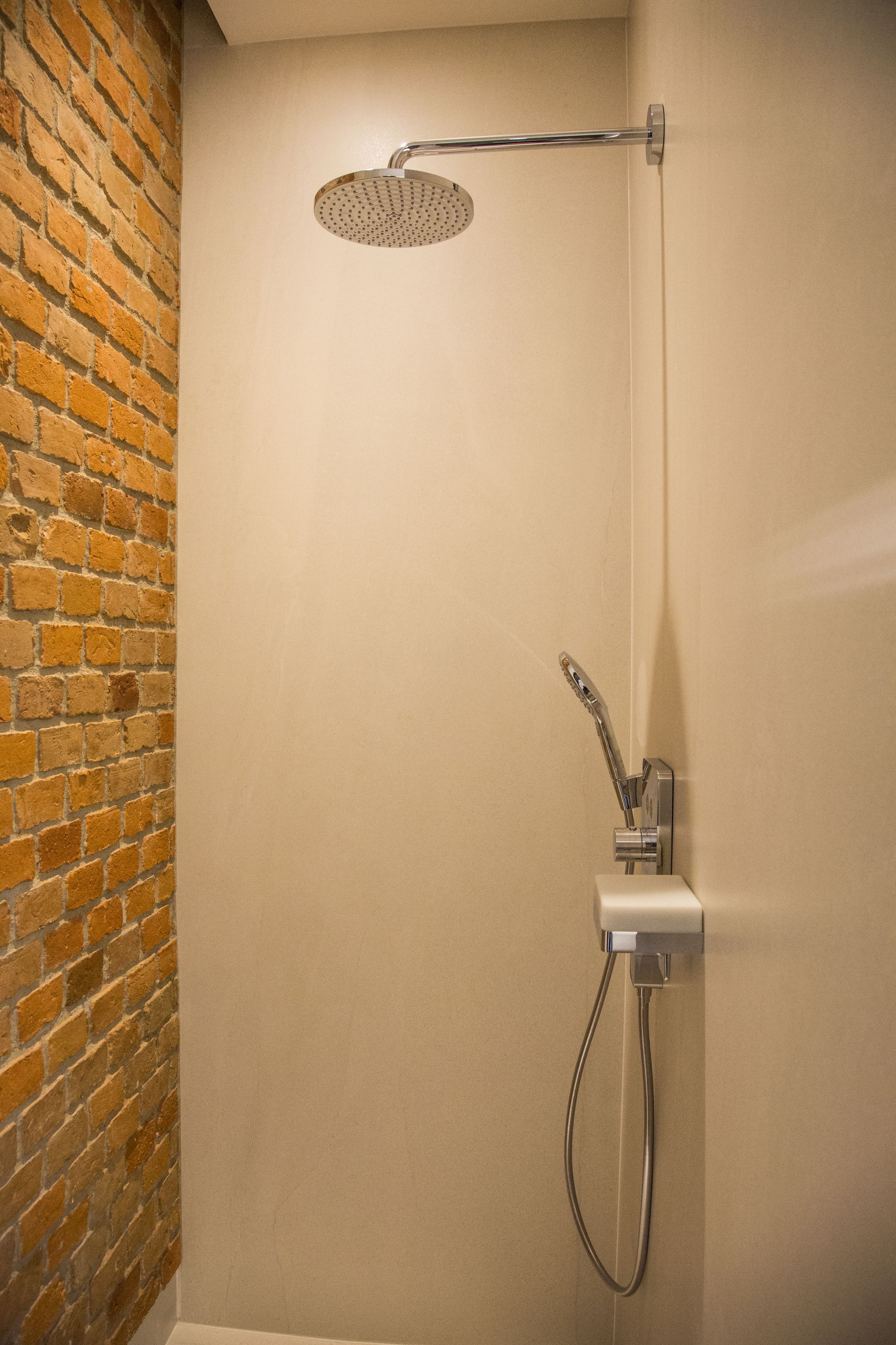 Une douche équipée d’un pommeau de douche à main et de commandes murales.