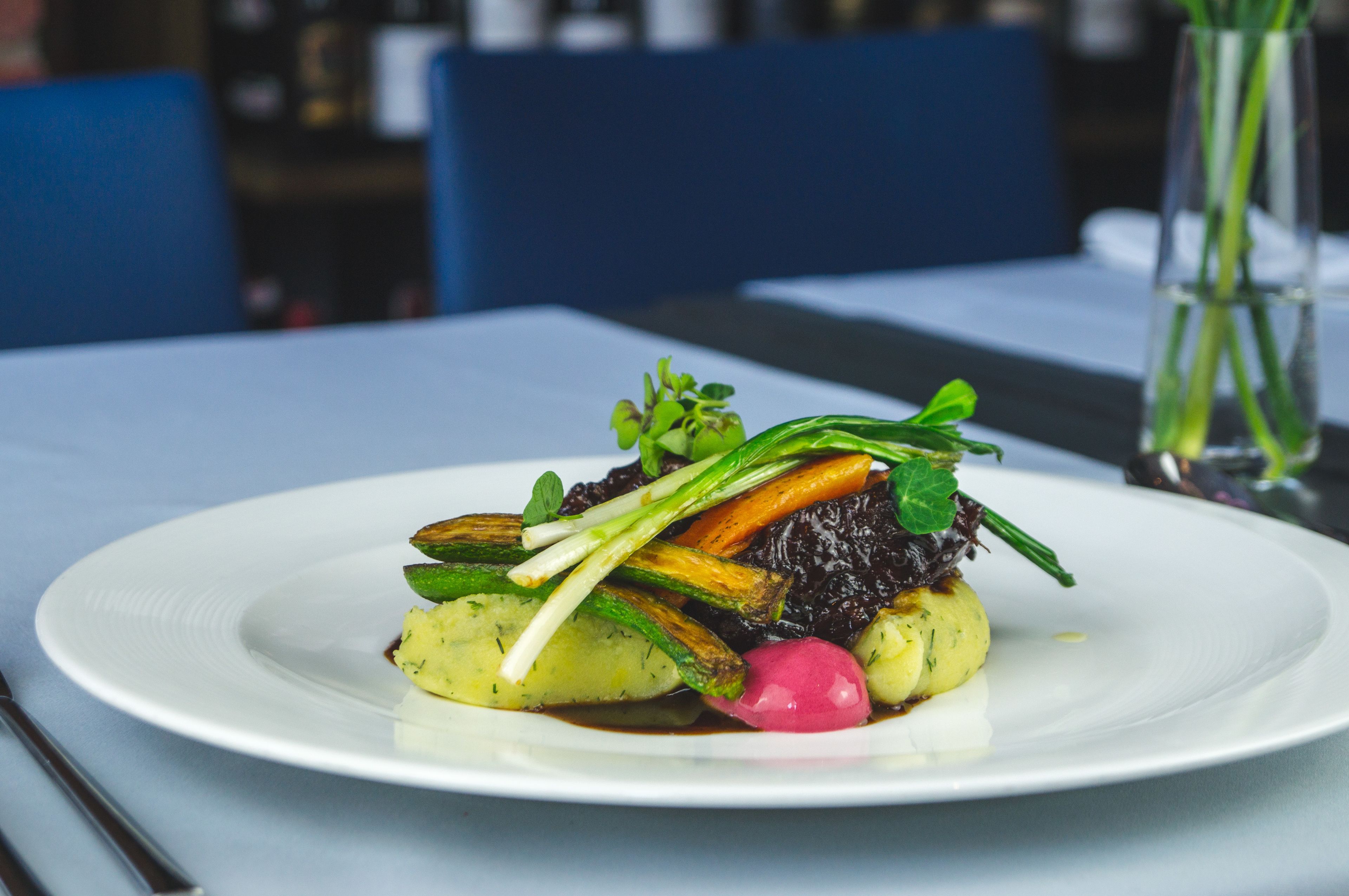 A white plate with a dish of vegetables and greens on a table.