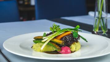 A white plate with a dish of vegetables and greens on a table.
