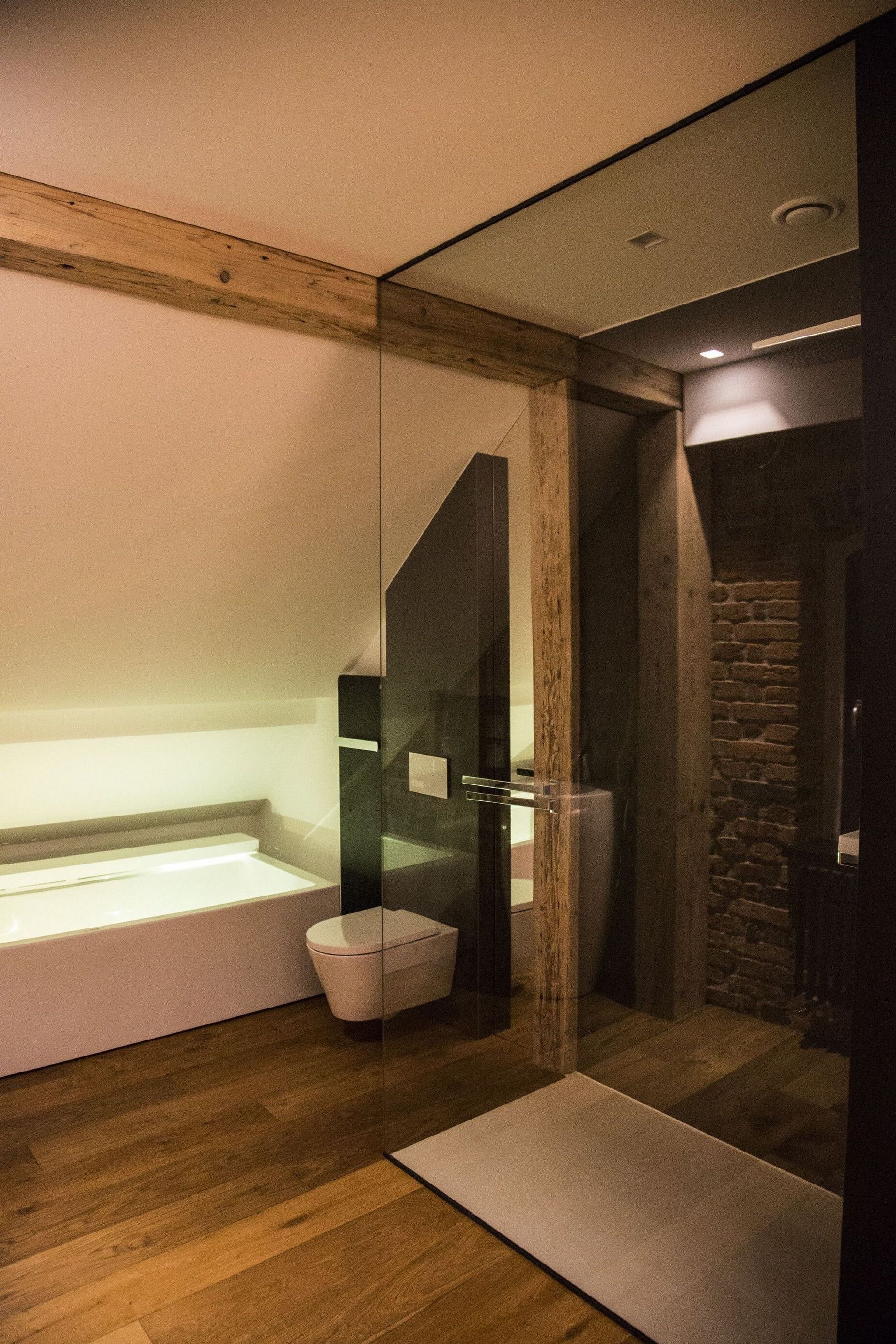A modern bathroom with a glass-enclosed shower, a wooden floor, and a built-in bathtub.