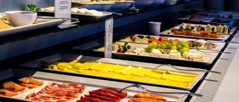 Ein Buffet mit verschiedenen Speisen, darunter Fleisch, Käse und Obst.