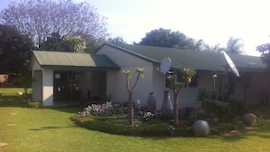 Una casa con techo verde, antena parabólica y jardín con flores y plantas.