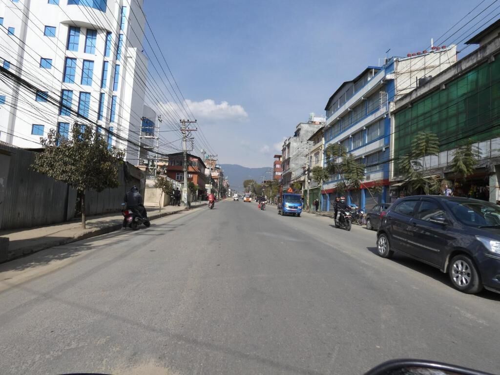 A street with buildings on both sides, vehicles, and a clear sky.