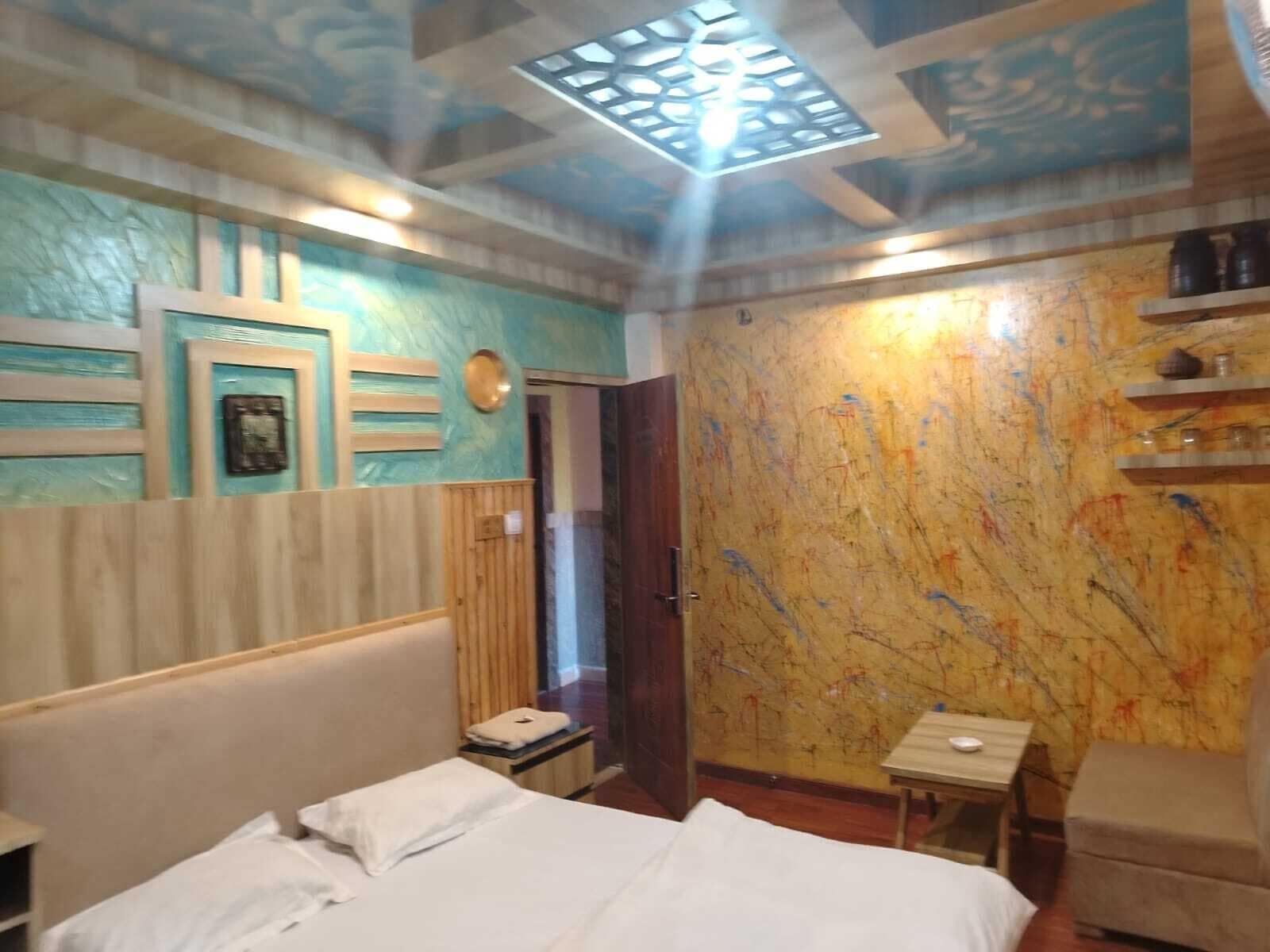 A hotel room with a bed, a small table, and a shelf with jars.