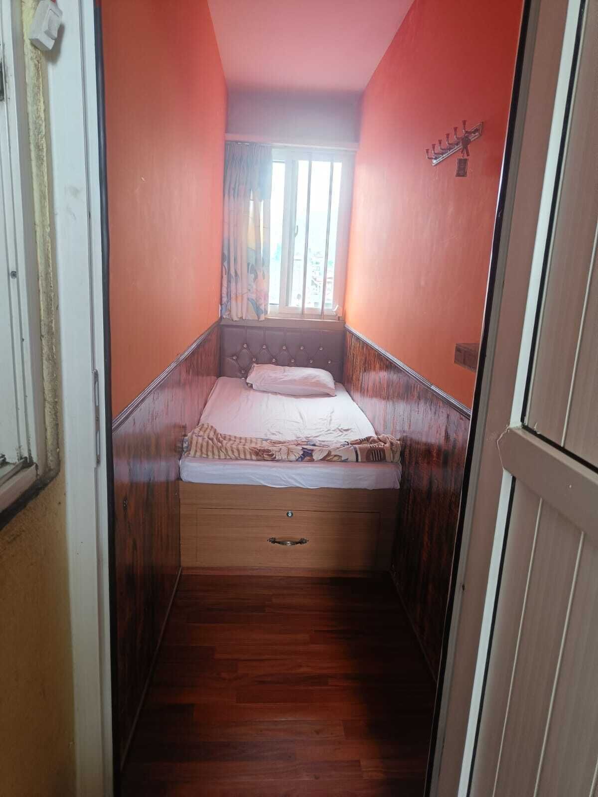 A narrow room with a bed, a window, and a door.