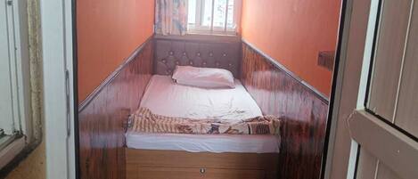 A narrow room with a bed, a window, and a door.