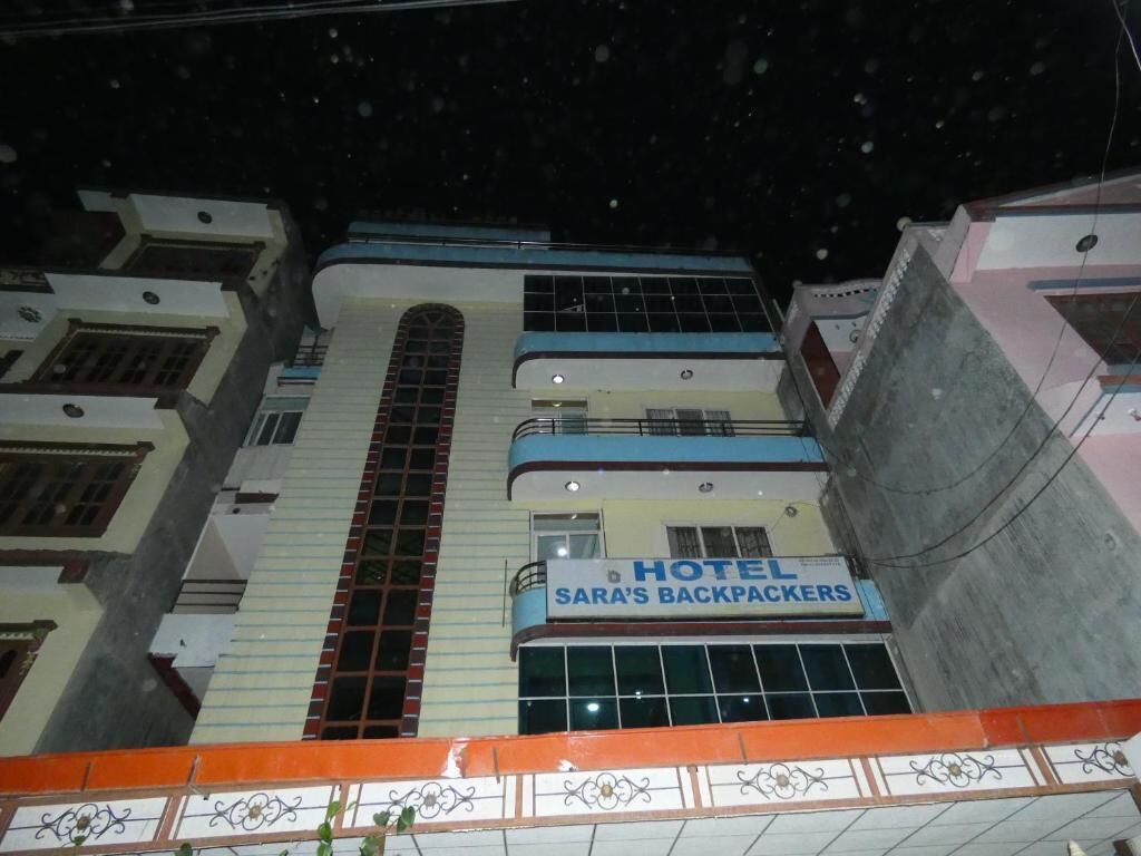 Un edificio de varios pisos con un letrero que dice 'SARA'S BACKPACKERS HOTEL' en la planta baja.