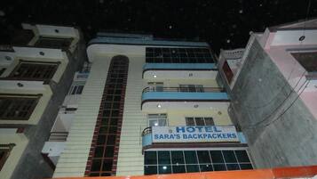 Un edificio de varios pisos con un letrero que dice 'SARA'S BACKPACKERS HOTEL' en la planta baja.