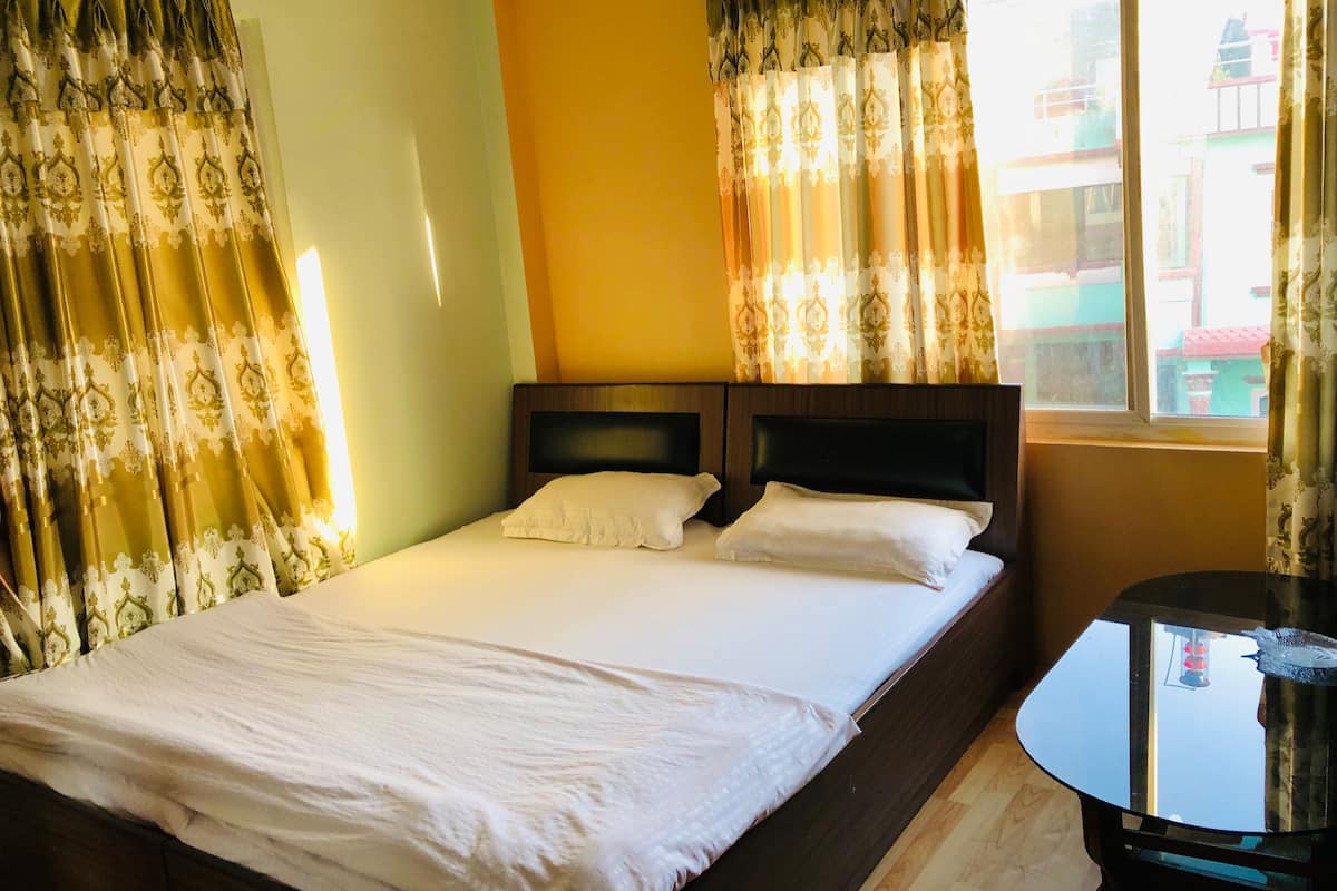 Una habitación de hotel con una cama, una mesita de noche y cortinas.