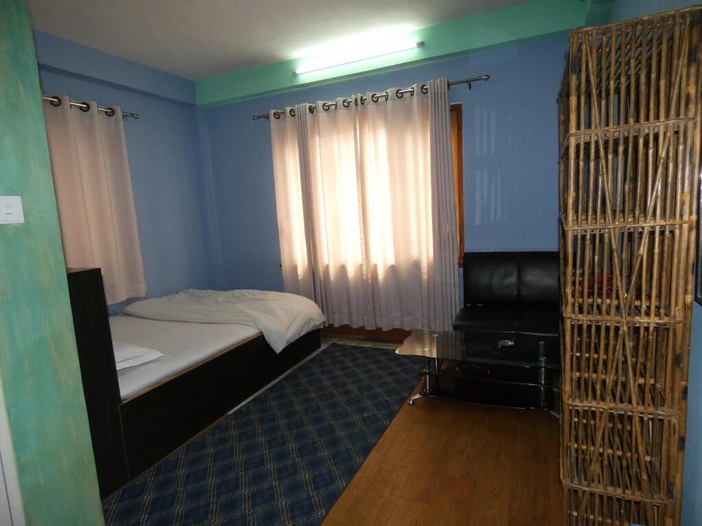 Ein Zimmer mit einem Bett, einem Fernseher und einem Bambusparavan.