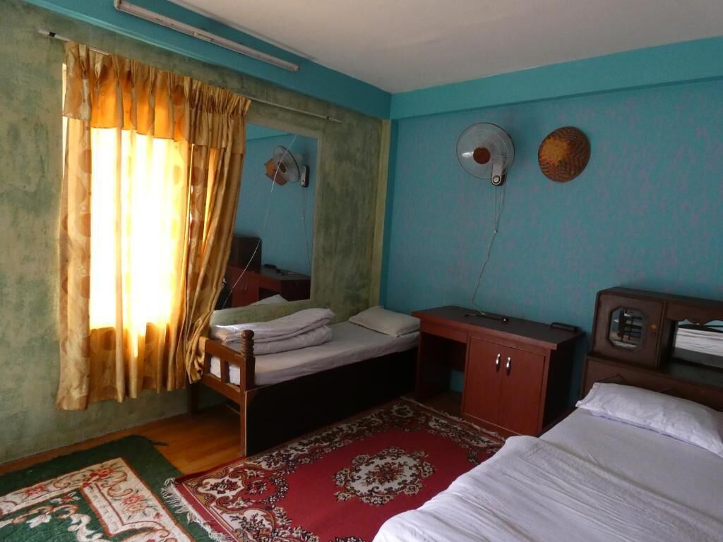 A room with a bed, a desk, a chair, a wardrobe, and a window with curtains.