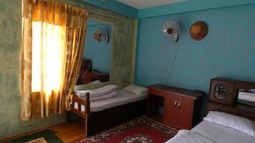 A room with a bed, a desk, a chair, a wardrobe, and a window with curtains.