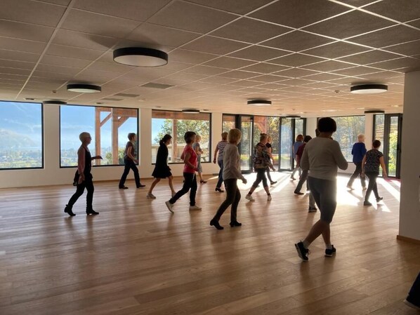 A spacious room with large windows and a wooden floor, suitable for group activities or meetings.