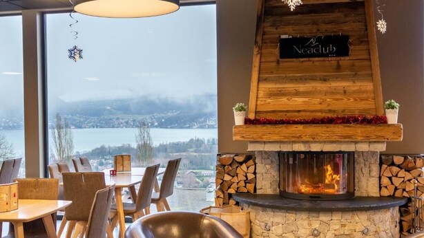 Un espacio lounge acogedor con chimenea de piedra, detalles de madera y vista a un lago.