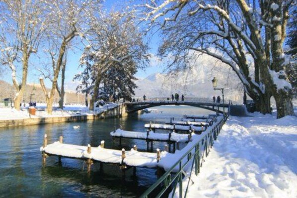 A snow-covered bridge over a river with snow on the banks and trees.