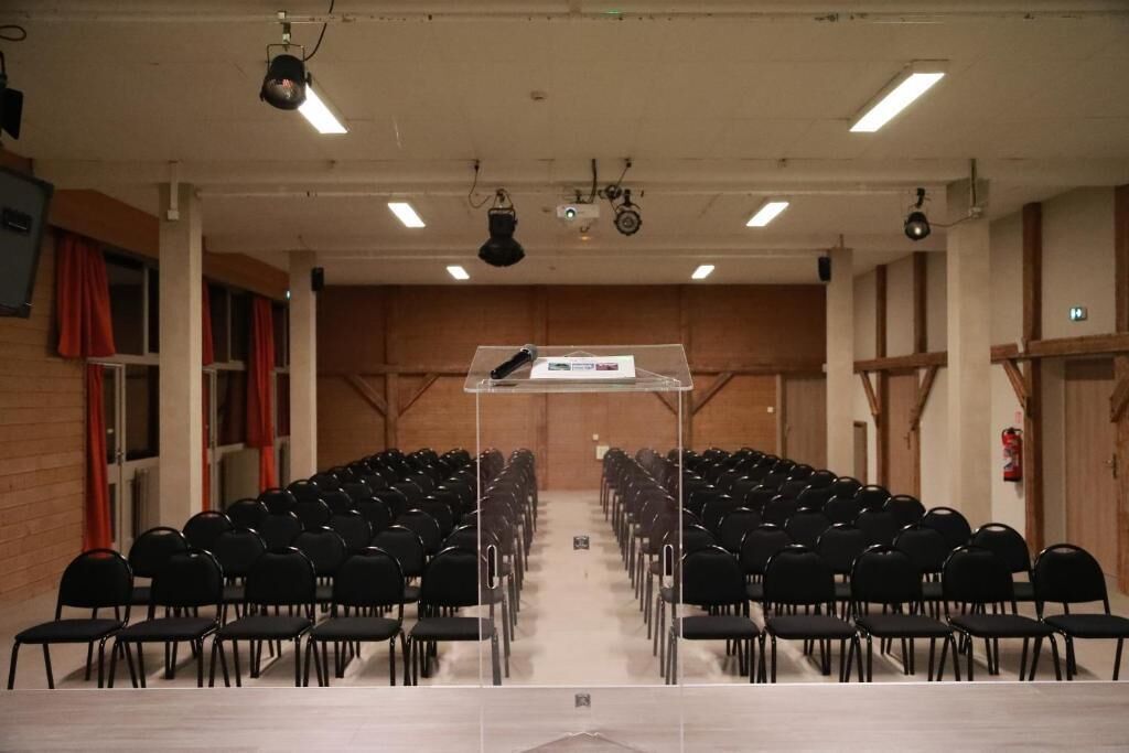 A conference room with rows of black chairs, a central table, and overhead lighting.