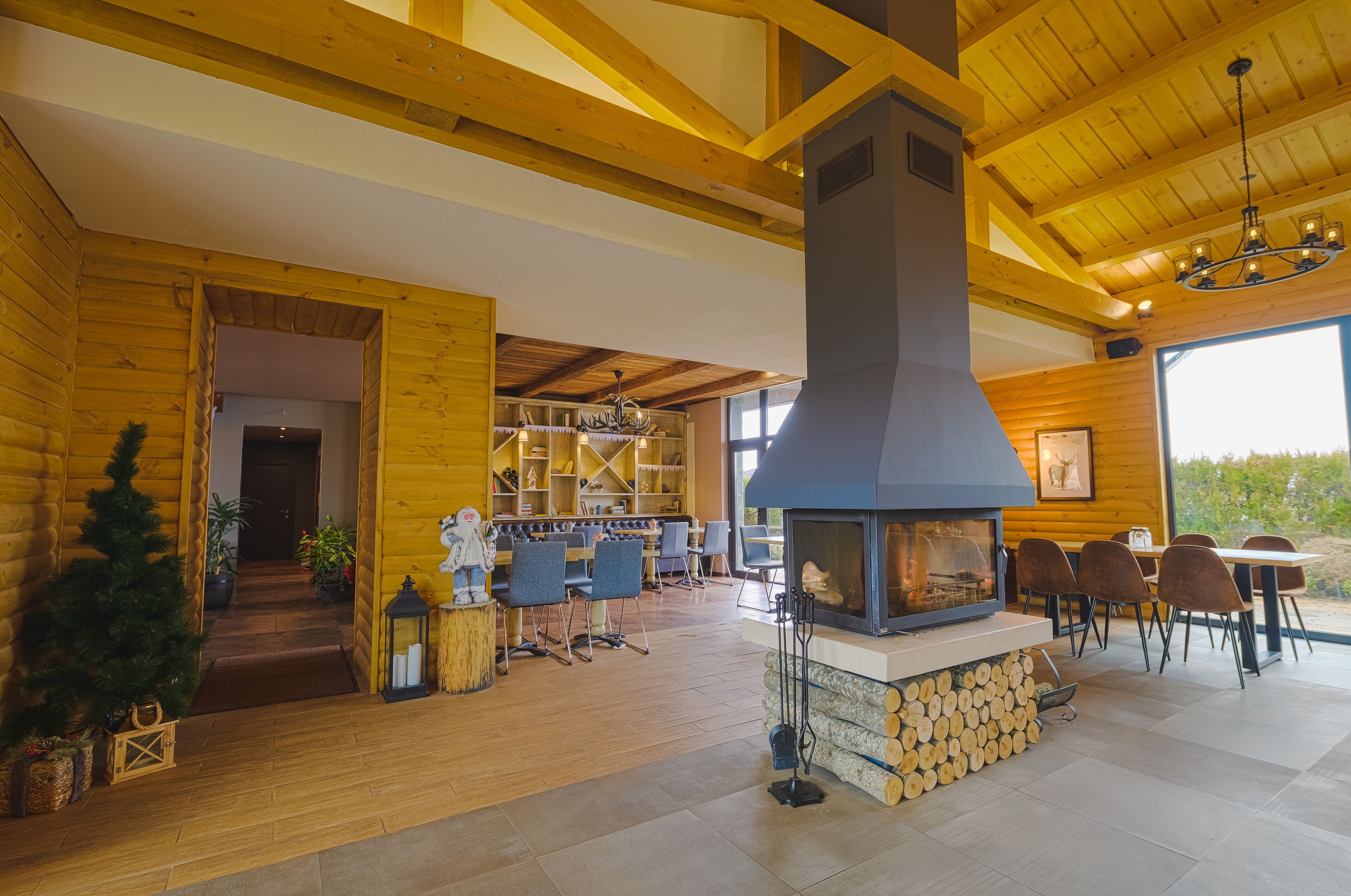 A spacious wooden interior with a fireplace, dining area, and a view through large windows.