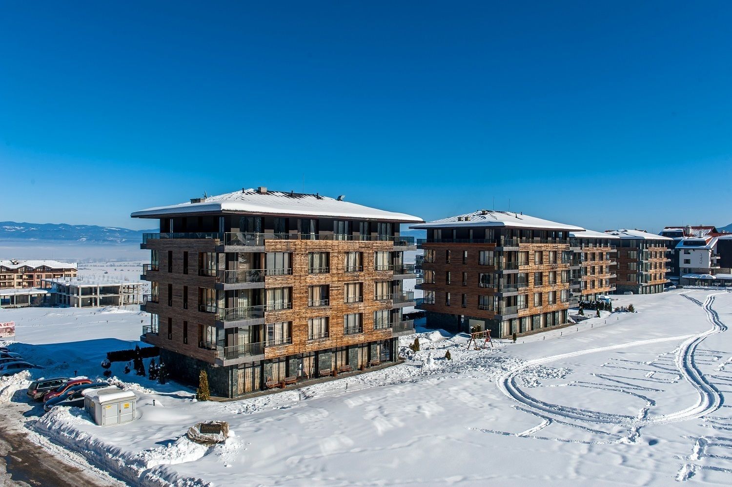 Ein modernes, mehrstöckiges Hotel mit verschneitem Dach in einer verschneiten Landschaft bei klarem Himmel.