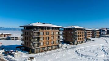 Een modern meerhoog hotel met een sneeuwbedekte dak, gelegen in een besneeerd landschap met heldere lucht.