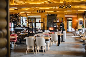 Un restaurant chaleureux avec un décor intérieur en bois, des tables, des chaises et une cheminée.