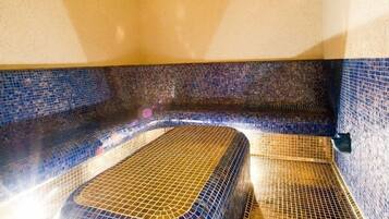 A room with a mosaic-tiled bathtub, a ceiling with a starry design, and a wall with a blue mosaic pattern.