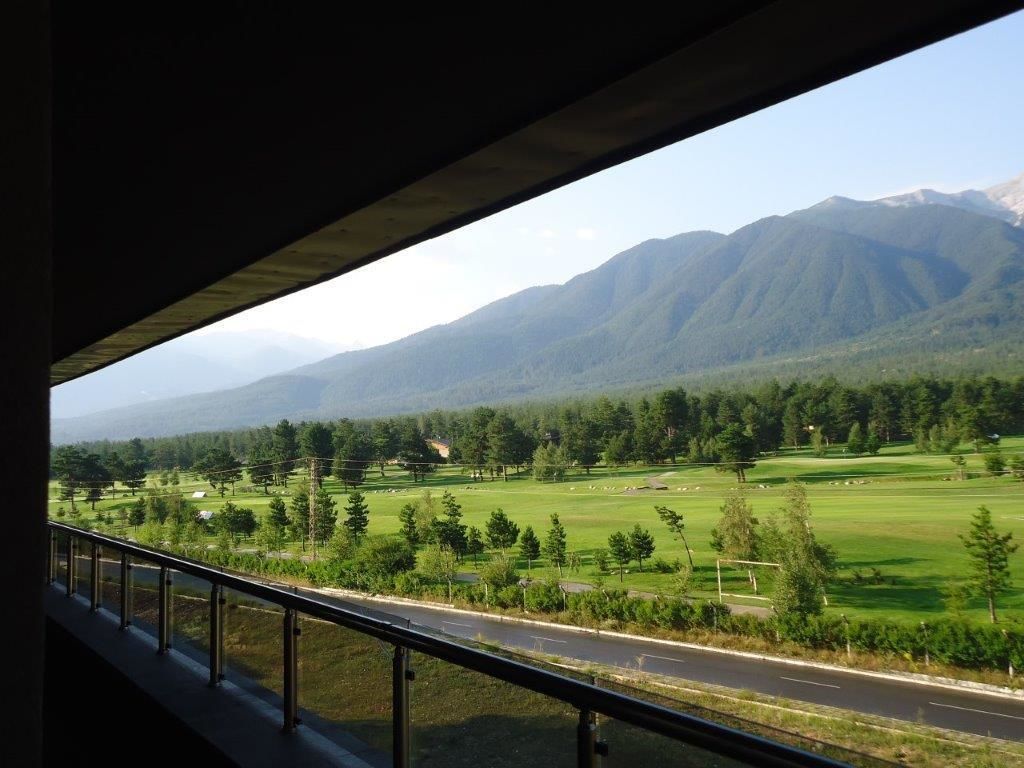 Vista desde un balcón sobre un paisaje verde con montañas al fondo.